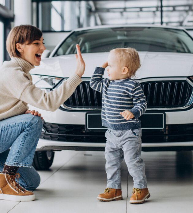 Woman with baby son choosing a car in a car salon Woman with baby son choosing a car in a car salon